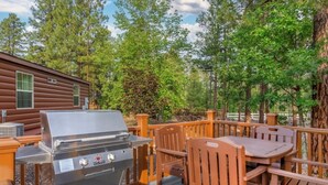 An outdoor deck with a grill, wooden chairs, and a table. - Pinetop | Family Cabin Retreat |  local hikes | 2BR (Pinetop)