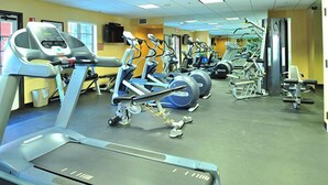 Un gimnasio con cintas de correr, elípticas y equipo de pesas.