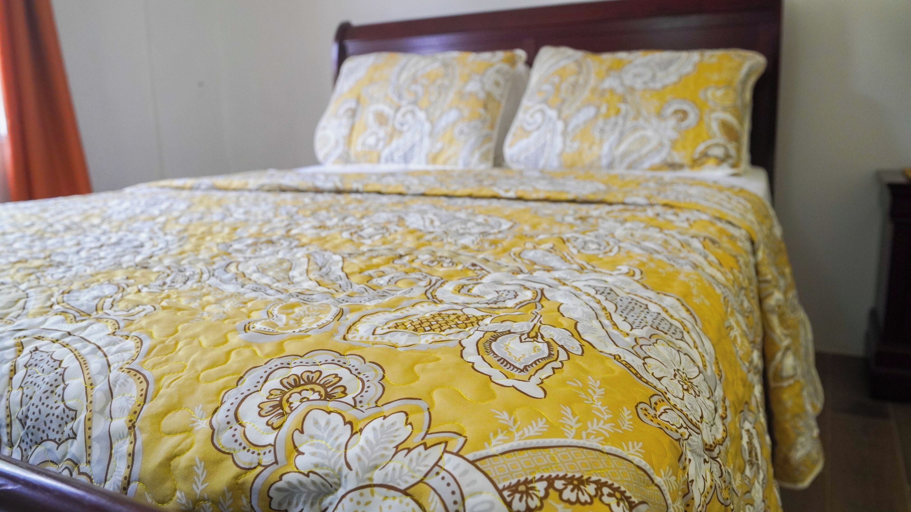 A bed with a patterned bedspread and two pillows.