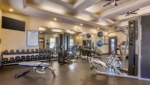 Une salle de sport équipée de divers appareils d’exercice, notamment des haltères, des tapis de course et des appareils de musculation.