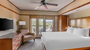 Une chambre d’hôtel avec un grand lit, une télévision, une chaise, un bureau et un balcon avec vue.