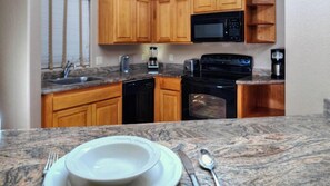 Compact kitchen with microwave, toaster, coffee maker, dishwasher, and oven.