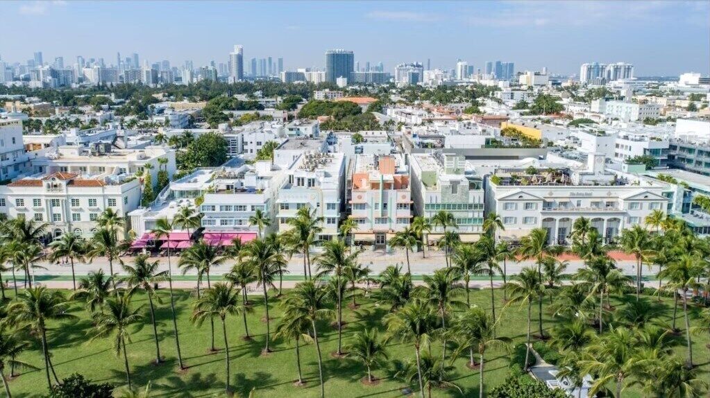 Un paisaje urbano costero con una mezcla de edificios modernos e históricos, palmeras y cielo despejado.