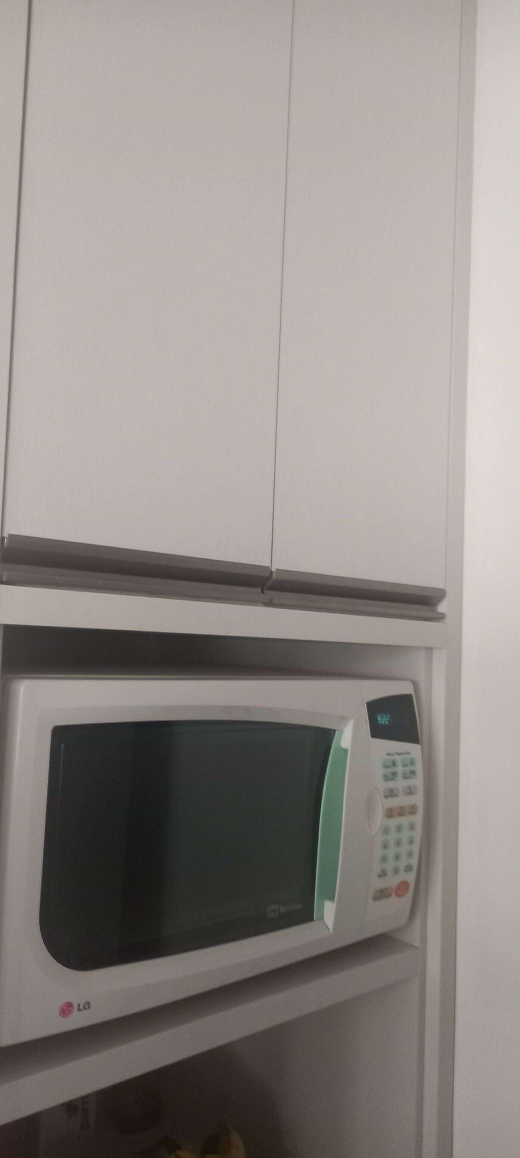 A microwave oven with a digital display and control panel, mounted on a white cabinet.