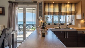 A modern kitchen with a central island, a view of the sea, and a dining area with a chair. - Bay View House with amazing view (Petalidi)