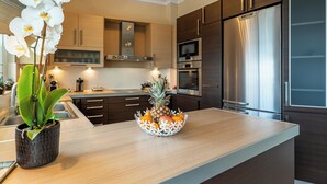 A modern kitchen with wooden cabinets, stainless steel appliances, and a central island with a fruit bowl and orchids. - Bay View House with amazing view (Petalidi)