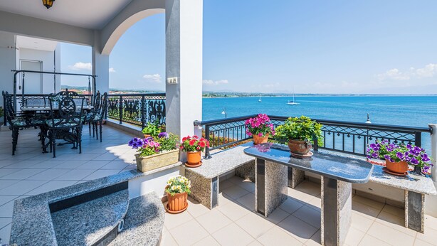 A balcony with outdoor furniture, potted plants, and a view of the sea. - Bay View House with amazing view (Petalidi)