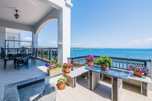 A balcony with outdoor furniture, potted plants, and a view of the sea. - Bay View House with amazing view (Petalidi)