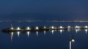 A waterfront view with a pier, calm water, and distant city lights. - Bay View House with amazing view (Petalidi)