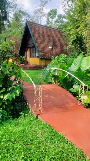Une maison avec un toit en pente et un chemin rouge menant à l’entrée.