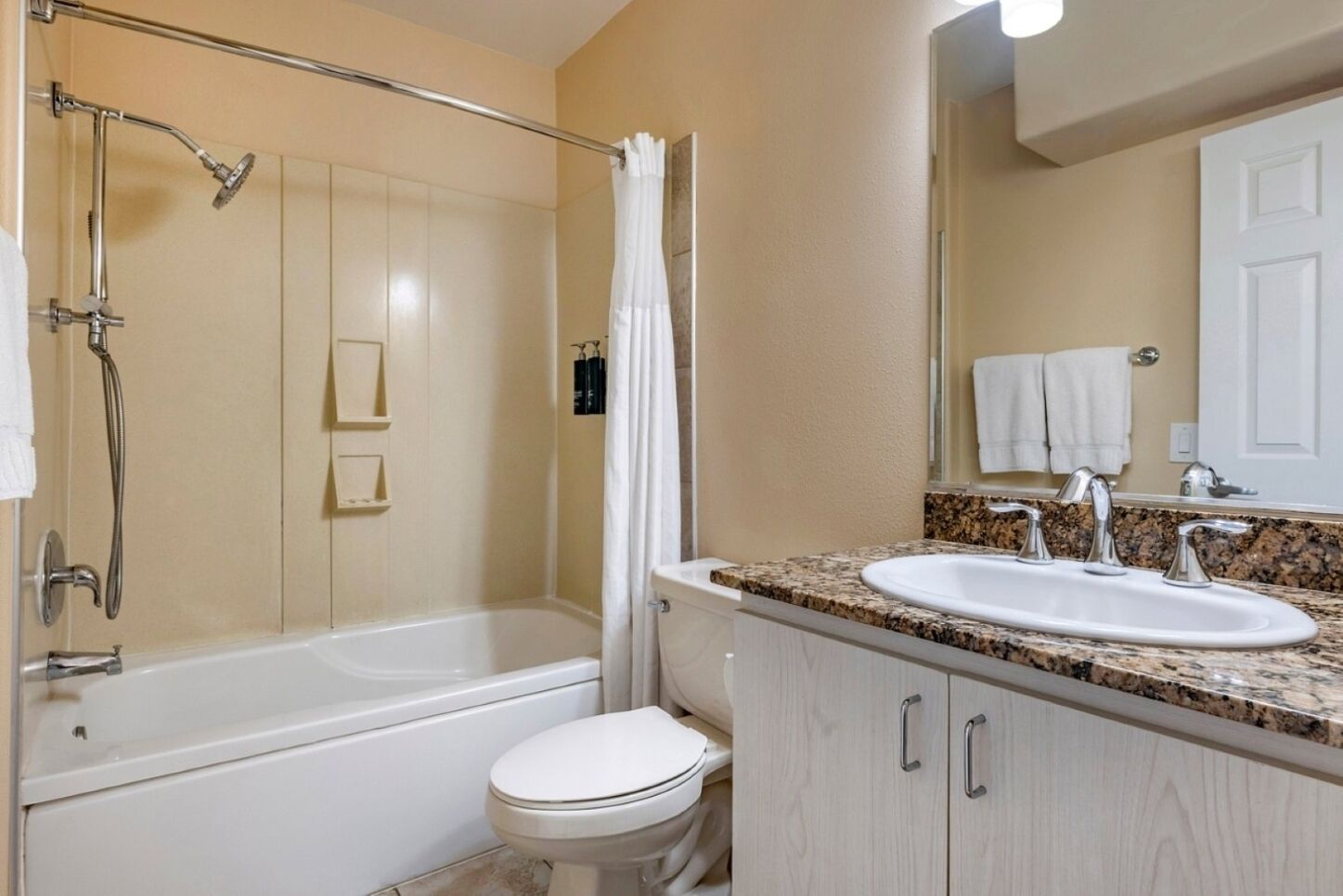 Ein Badezimmer mit Badewanne, Dusche, Toilette und einem Waschbecken mit einer Granit-Arbeitsplatte.