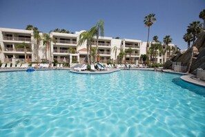 Ein Swimmingpool mit Liegestühlen und Palmen.