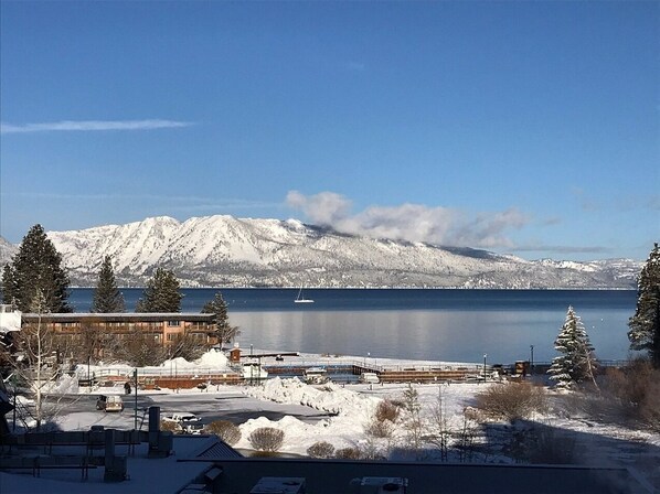 A snow-covered landscape with a body of water, mountains, and a building with a dock.