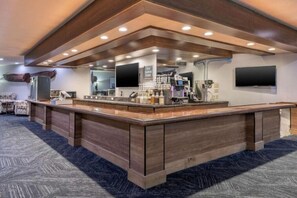 Relax in our contemporary lobby, featuring a central bar with self-service options and comfortable seating areas.