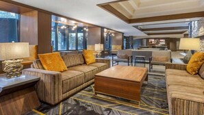 Un hall d’entrée spacieux au design moderne, comprenant un grand ensemble de canapés, une table basse en bois et un tapis à motifs.
