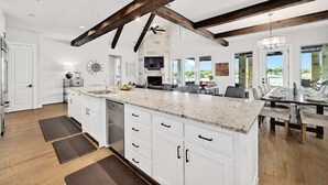 Una cocina amplia con una isla grande, vigas de madera y un comedor con vistas.