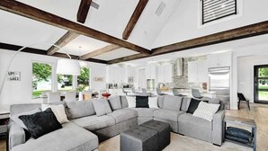 Una sala de estar moderna con un sofá modular, una mesa de centro y una cocina al fondo.