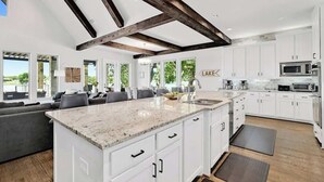 Una cocina moderna con armarios blancos, encimeras de granito y una isla grande.