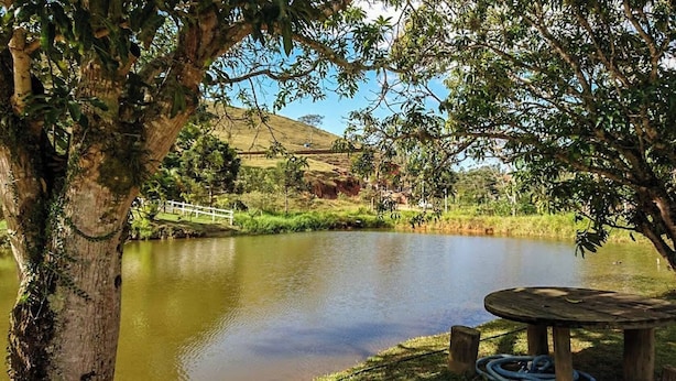 A serene lakeside setting with a wooden bench and a white fence. - Pousada Rancho da Mata (Valenca)