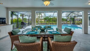 Un coin repas avec une table en verre, des chaises en osier et un ventilateur de plafond.