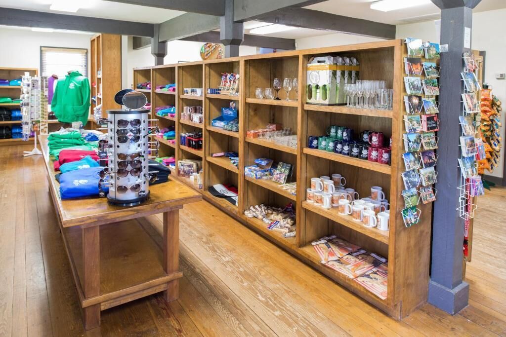 A store with wooden shelves stocked with sunglasses, mugs, and books.