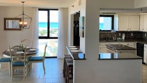Une cuisine moderne avec des armoires blanches, un îlot central et une vue sur l’océan.