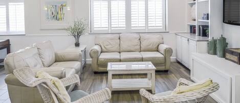 Ein modernes Wohnzimmer mit zwei Sofas, einem Couchtisch und Korbstühlen.