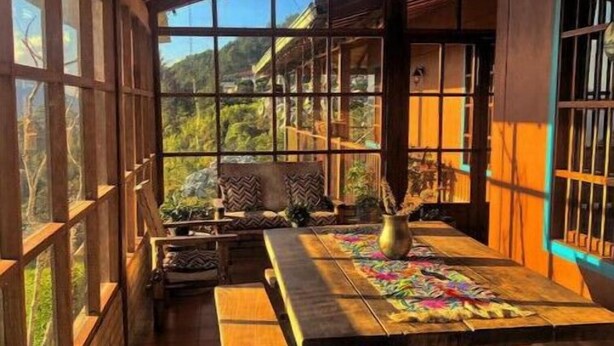 Ein traditioneller japanischer Raum mit Tatami-Matten, Holzmöbeln und großen Fenstern mit Blick ins Freie.