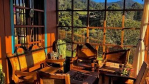Ein gemütliches Zimmer mit großem Fenster und Blick auf eine Berglandschaft. Ein Holztisch und Stühle bieten Platz zum Sitzen.