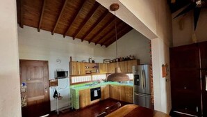 Eine Küche mit Holzausstattung, einem Edelstahl-Kühlschrank und einer hängenden Pendelleuchte.