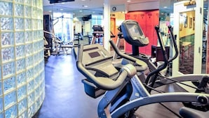 Un gimnasio con equipamiento de ejercicio, una pared de azulejos y una puerta roja al fondo.