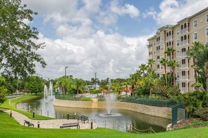 A hotel with a courtyard featuring a fountain, palm trees, and a pool.