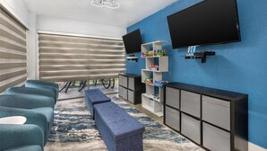 Una sala de estar moderna con televisor de pantalla plana, pared de acento azul, estante empotrado con juegos de mesa y un banco.