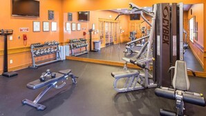 A gym with exercise equipment, a mirrored wall, and a television.