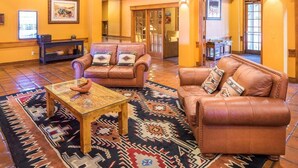 A lobby with leather sofas, a coffee table, and a patterned rug.