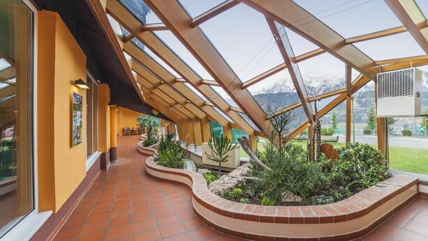 A covered walkway with a view of mountains, a tiled floor, and a planter with plants. - Schladming | Friends Alpine Stay | Pool + Spa | 2BR Condo (Schladming)