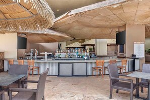 A bar area with a counter, bar stools, and a menu board.