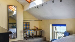 A small, cozy room with a sloped ceiling, a single bed, a chair, a small table, and a window with a view. - 3 bedroom accommodation in Skipton (Skipton)