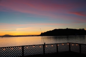 Vista al lago al atardecer, con un muelle y luces colgantes.