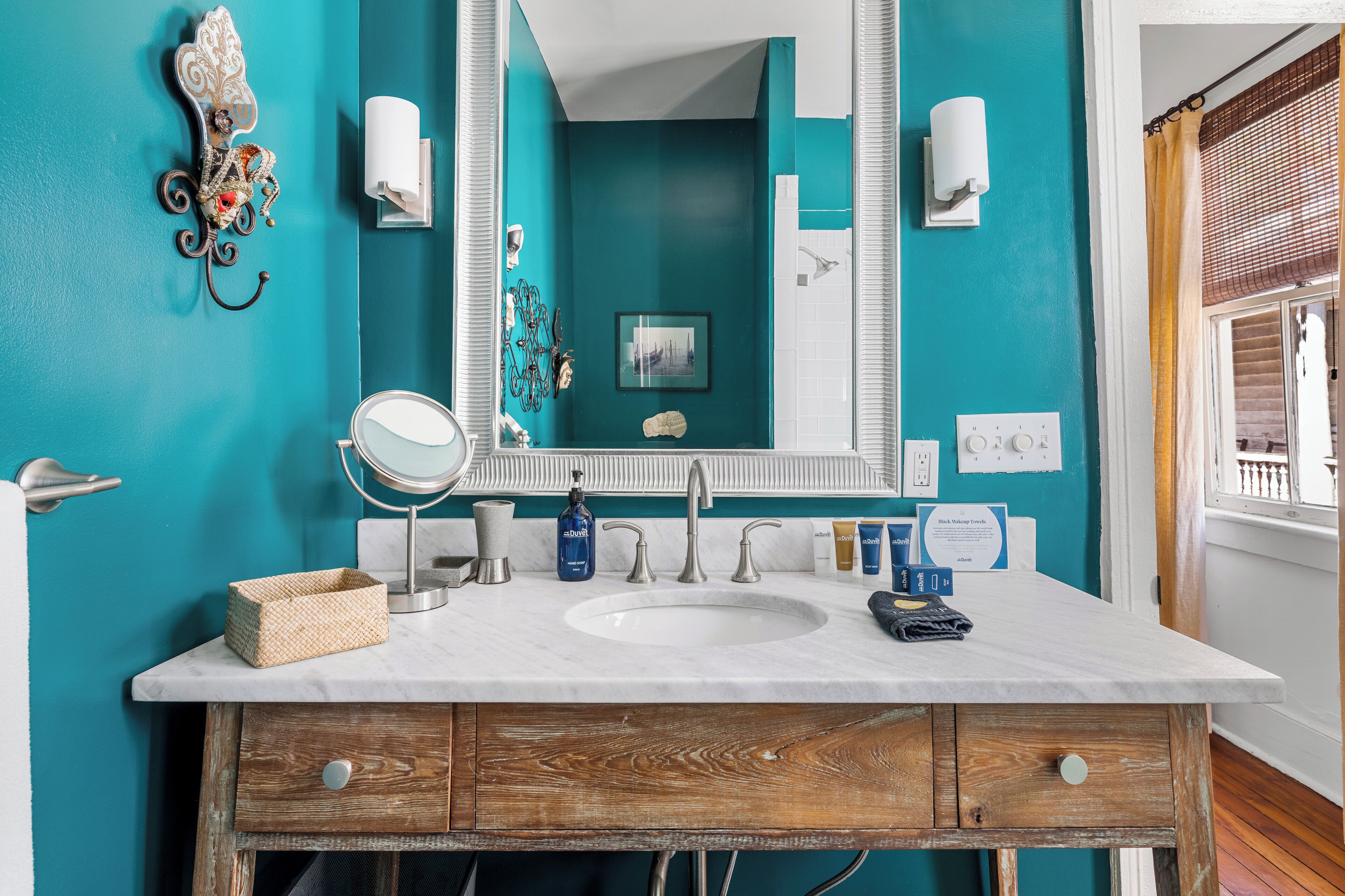A bathroom with a white sink, teal walls, and a wooden vanity.
