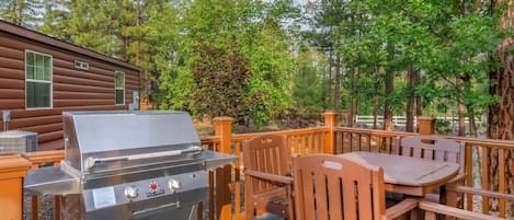 En uteplats med en grill, tränstolar och ett bord.