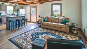 A spacious living area with a leather sofa, a coffee table, and a patterned rug. - Creek, Trails & Falls! Rural Red River Gorge Cabin (Campton)