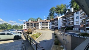 Un hotel a più piani con balconi, un parcheggio e cielo sereno.