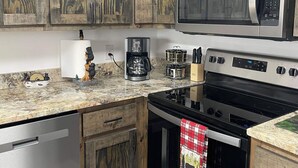 Una cucina con mobili in legno, un forno a microonde, un fornello e una lavastoviglie.