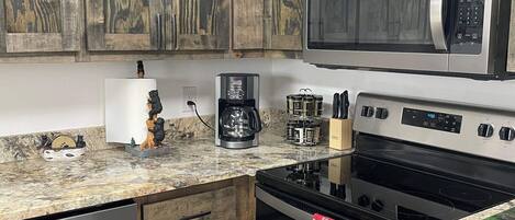Una cocina con armarios de madera, microondas, estufa y lavavajillas.