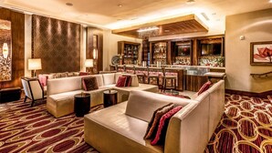 Eine Hotlellobby mit Barbereich, Sitzgelegenheiten und einem gemusterten Teppich.