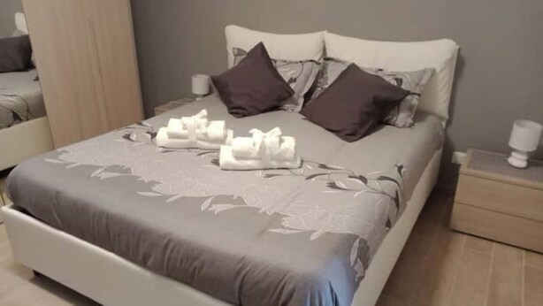A neatly made bed with a floral bedspread, two pillows, and a set of towels. - Rosetta's Experience (Roma)