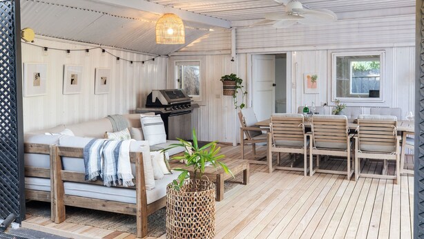 A covered outdoor living area with a sofa, dining table, chairs, and a grill. - Sol Coastal Retreat - Outdoor Spa and Sauna (Rosebud)
