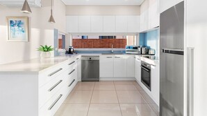 Una cocina moderna con armarios blancos, electrodomésticos de acero inoxidable y una isla central.