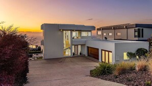 Una casa moderna de dos pisos con techo plano, ventanas grandes y un garaje.